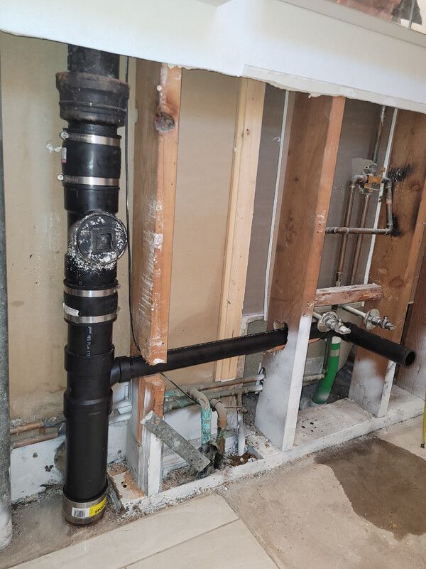 A bathroom sink is being remodeled with a lot of pipes coming out of it.