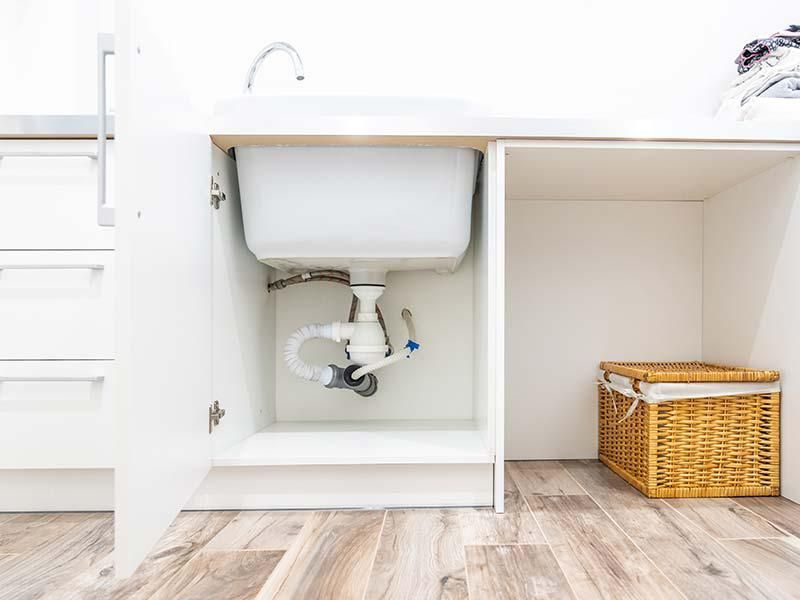 A sink is sitting under a cabinet in a laundry room.