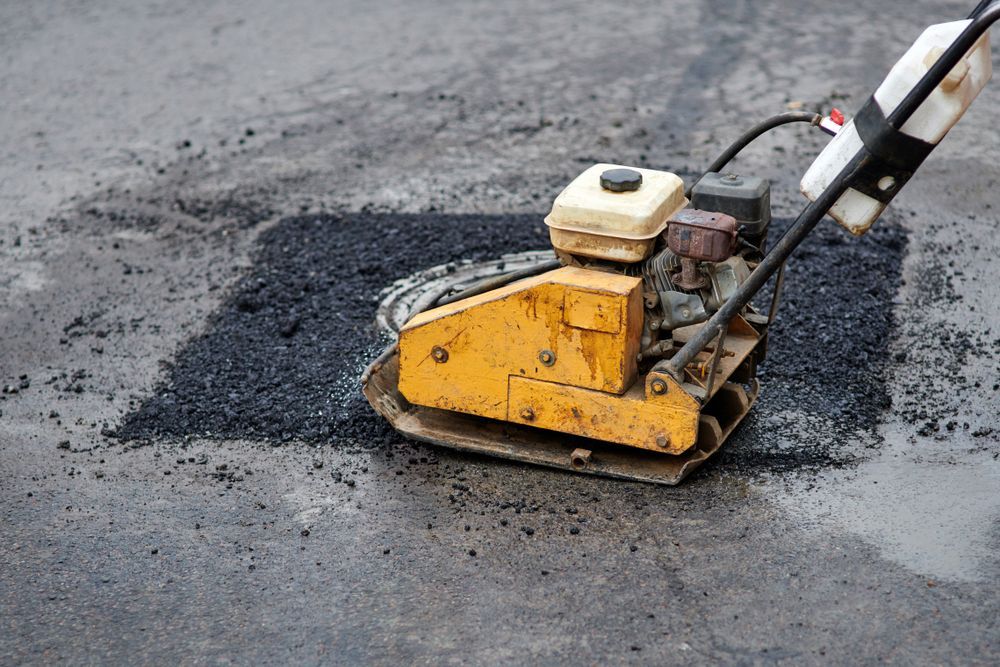 A Yellow Machine is Being Used to Patch a Hole in the Asphalt — Copp & Co Civil & Plant Hire in Airlie Beach, QLD