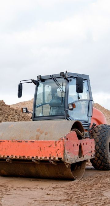 A Red and Black Construction Vehicle is Sitting on Top of a Dirt Field — Copp & Co Civil & Plant Hire in Cannonvale, QLD