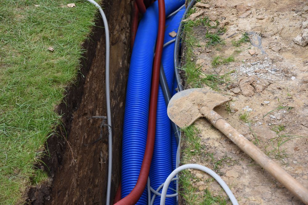 A Blue Pipe is Being Installed in a Trench Next to a Shovel — Copp & Co Civil & Plant Hire in Cannonvale, QLD