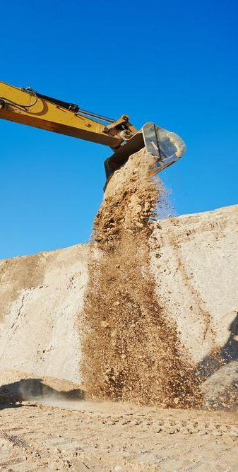 A Bulldozer is Pouring Dirt Into a Pile of Dirt — Copp & Co Civil & Plant Hire in Airlie Beach, QLD