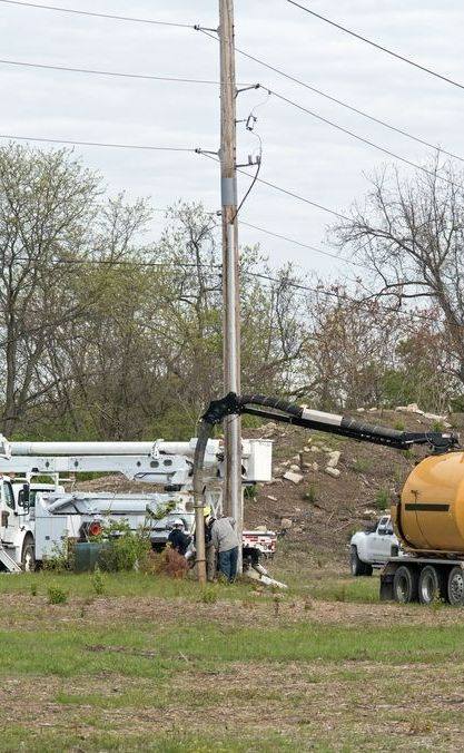 A Yellow Truck is Driving Down a Grassy Field Next to a Power Pole — Copp & Co Civil & Plant Hire in Airlie Beach, QLD