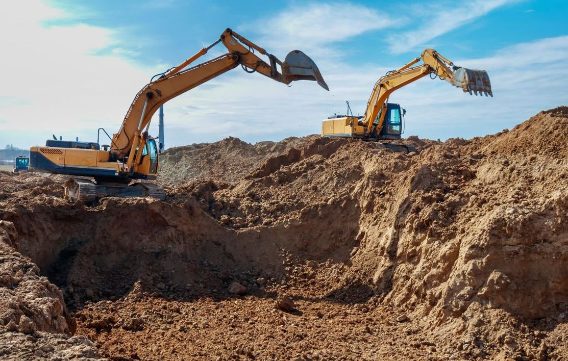 Two Excavators Are Digging a Hole in the Dirt on a Construction Site — Copp & Co Civil & Plant Hire in Bowen, QLD