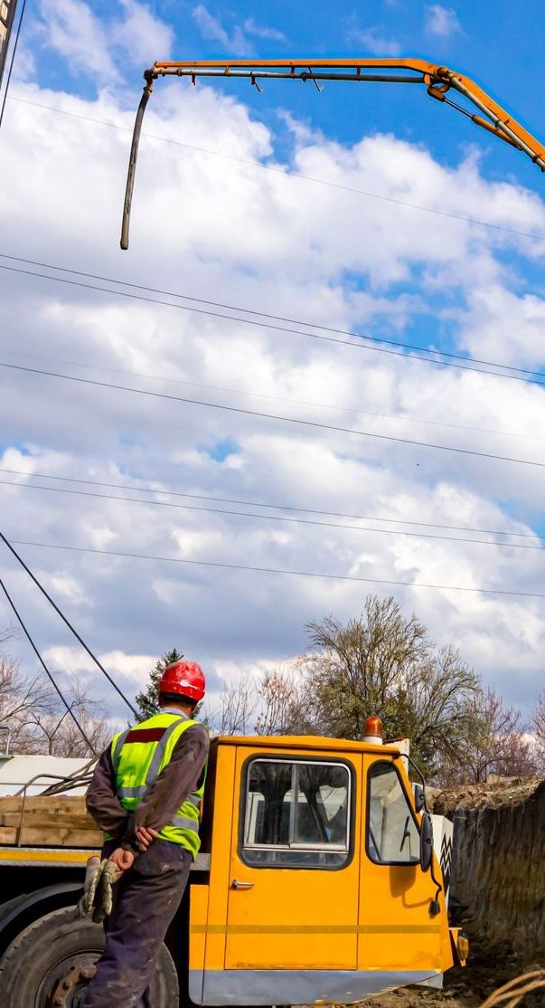 A Man is Standing Next to a Yellow Truck With a Crane Attached to It — Copp & Co Civil & Plant Hire in Cannonvale, QLD