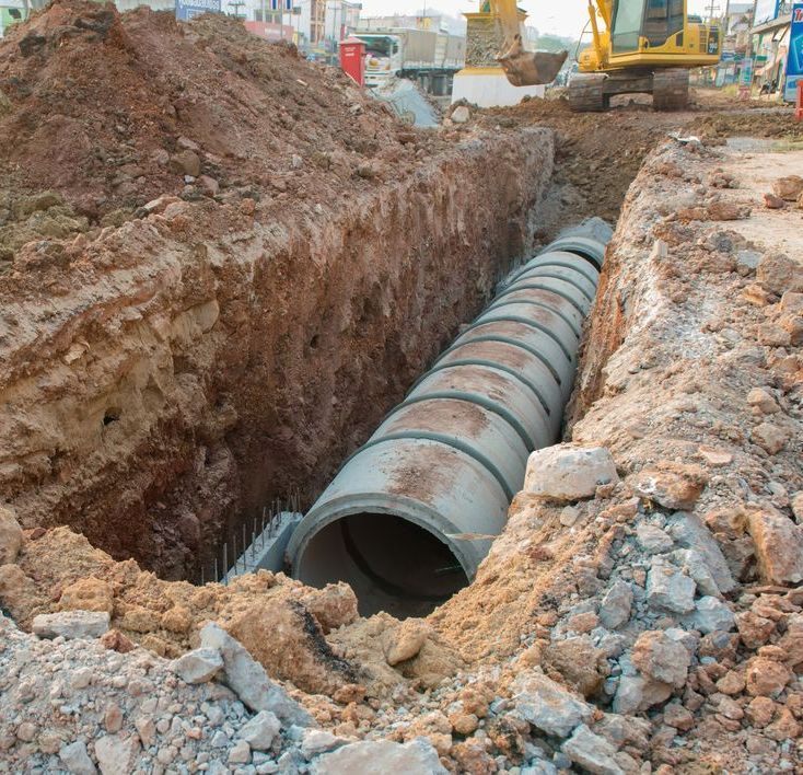A Large Concrete Pipe is Being Installed in a Trench — Copp & Co Civil & Plant Hire in Bowen, QLD
