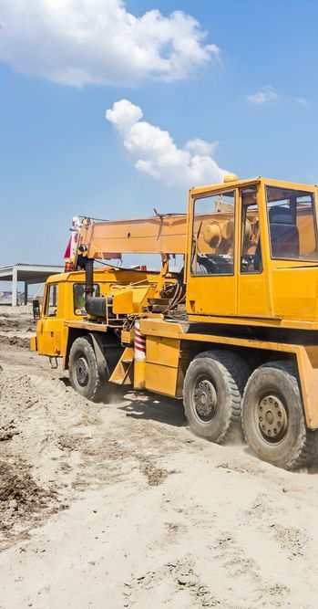 A Yellow Crane is Parked in the Dirt on a Construction Site — Copp & Co Civil & Plant Hire in Cannonvale, QLD