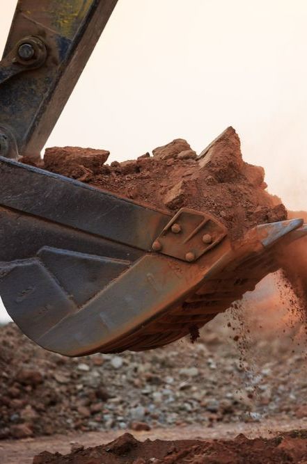 A Bulldozer is Scooping Dirt Out of a Bucket on a Construction Site — Copp & Co Civil & Plant Hire in Cannonvale, QLD