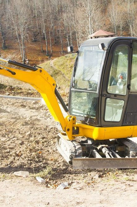 A Small Yellow Excavator is Sitting on Top of a Dirt Field — Copp & Co Civil & Plant Hire in Proserpine, QLD