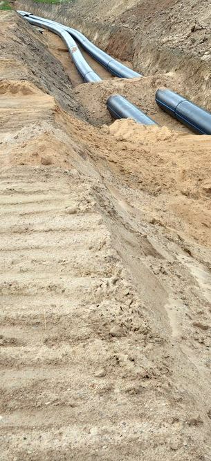 A Bunch of Pipes Are Laying in the Dirt — Copp & Co Civil & Plant Hire in Bowen, QLD