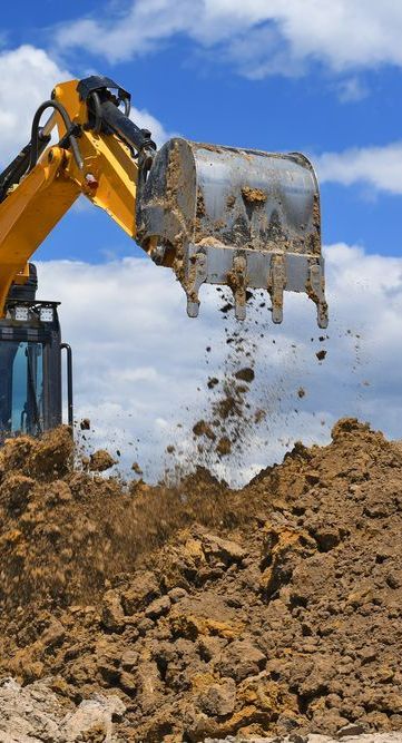 A Yellow Excavator is Digging a Pile of Dirt on a Construction Site — Copp & Co Civil & Plant Hire in Airlie Beach, QLD