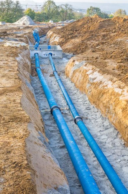 A Bunch of Blue Pipes Are Laying in the Dirt in a Trench — Copp & Co Civil & Plant Hire in Cannonvale, QLD