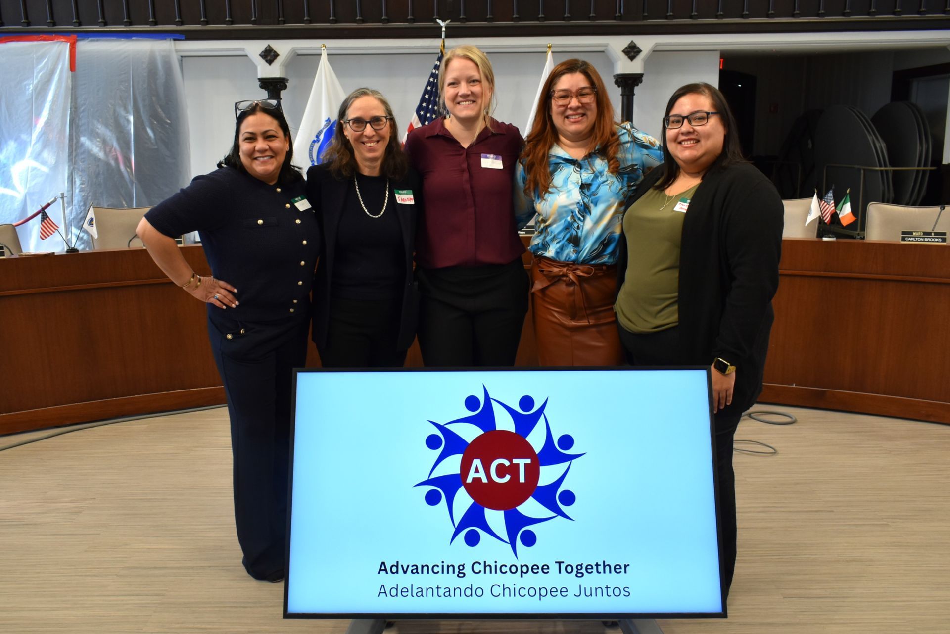 Five people from the ACT design team stand smiling with the Advancing Chicopee Together logo on screen