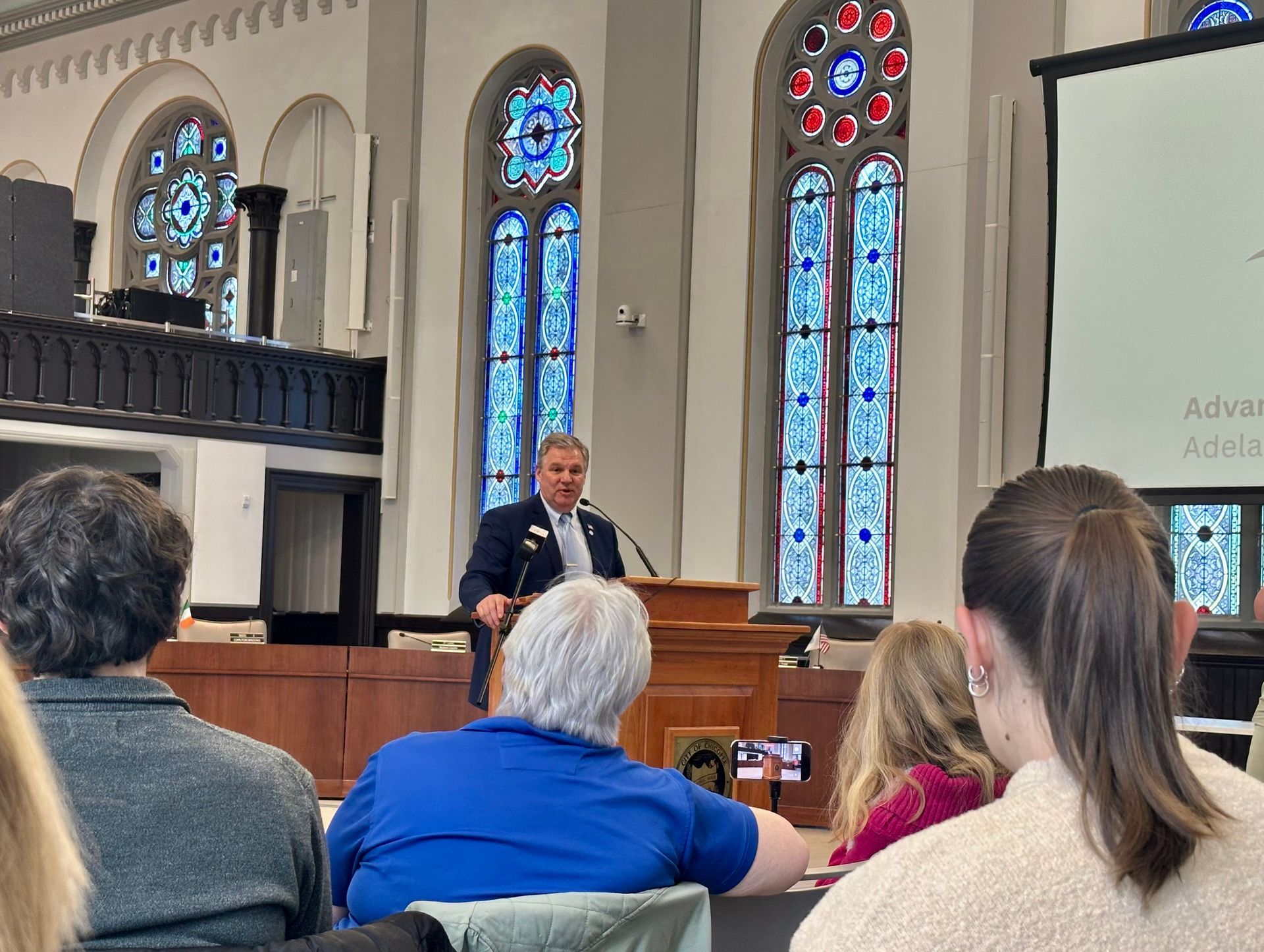 Audience looks on as Mayor John Vieau speaks at podium