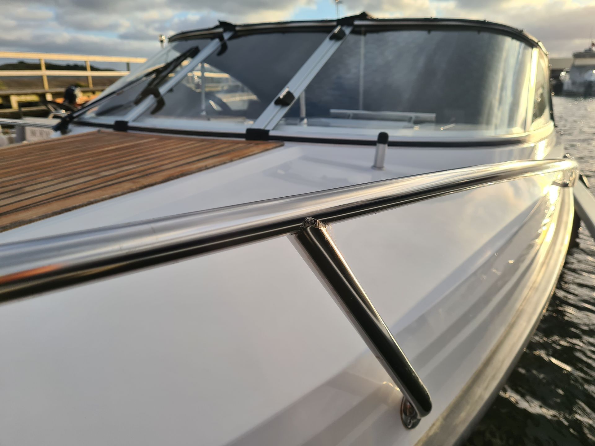 A white boat with a wooden deck is in the water