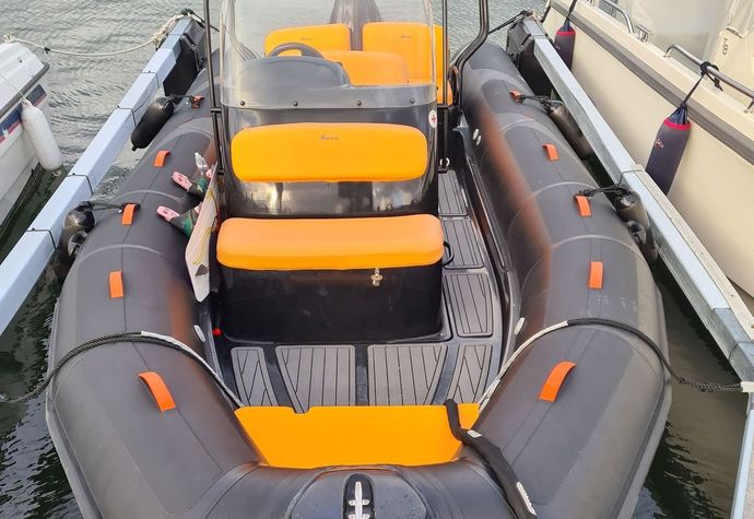 A black and yellow inflatable boat is docked at a dock.