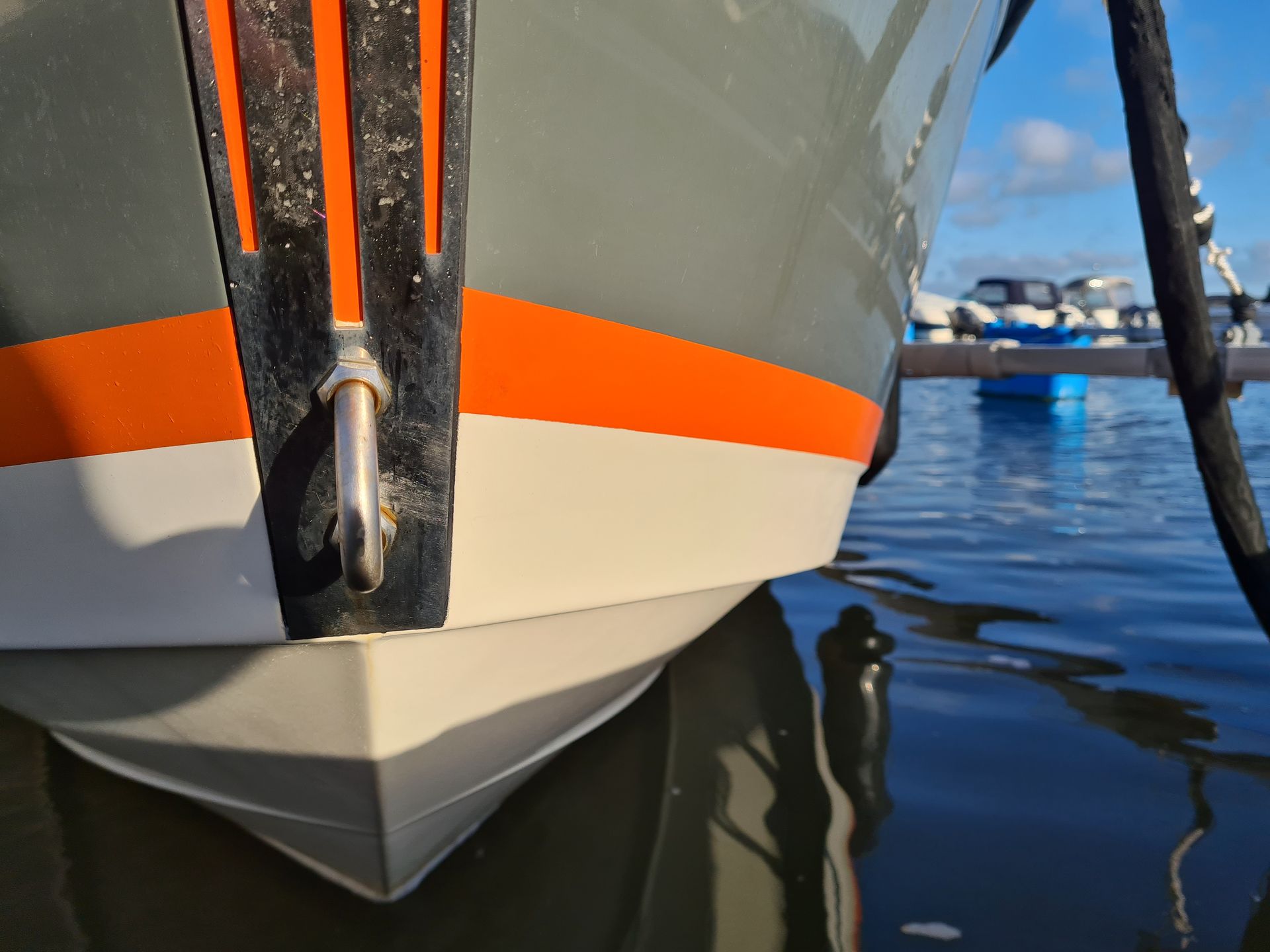 A boat with orange stripes is docked in the water