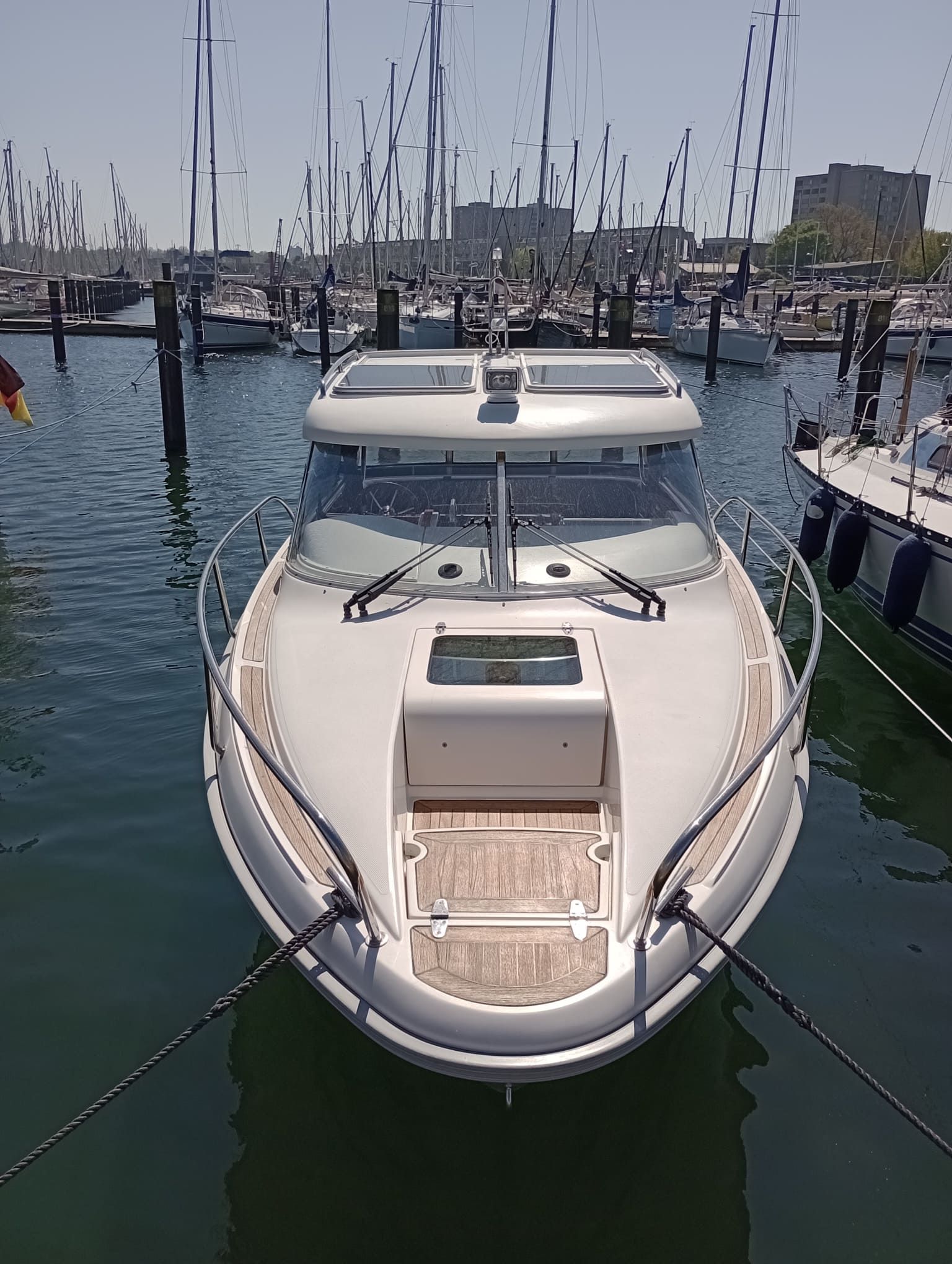 A white boat is docked in a marina surrounded by other boats.