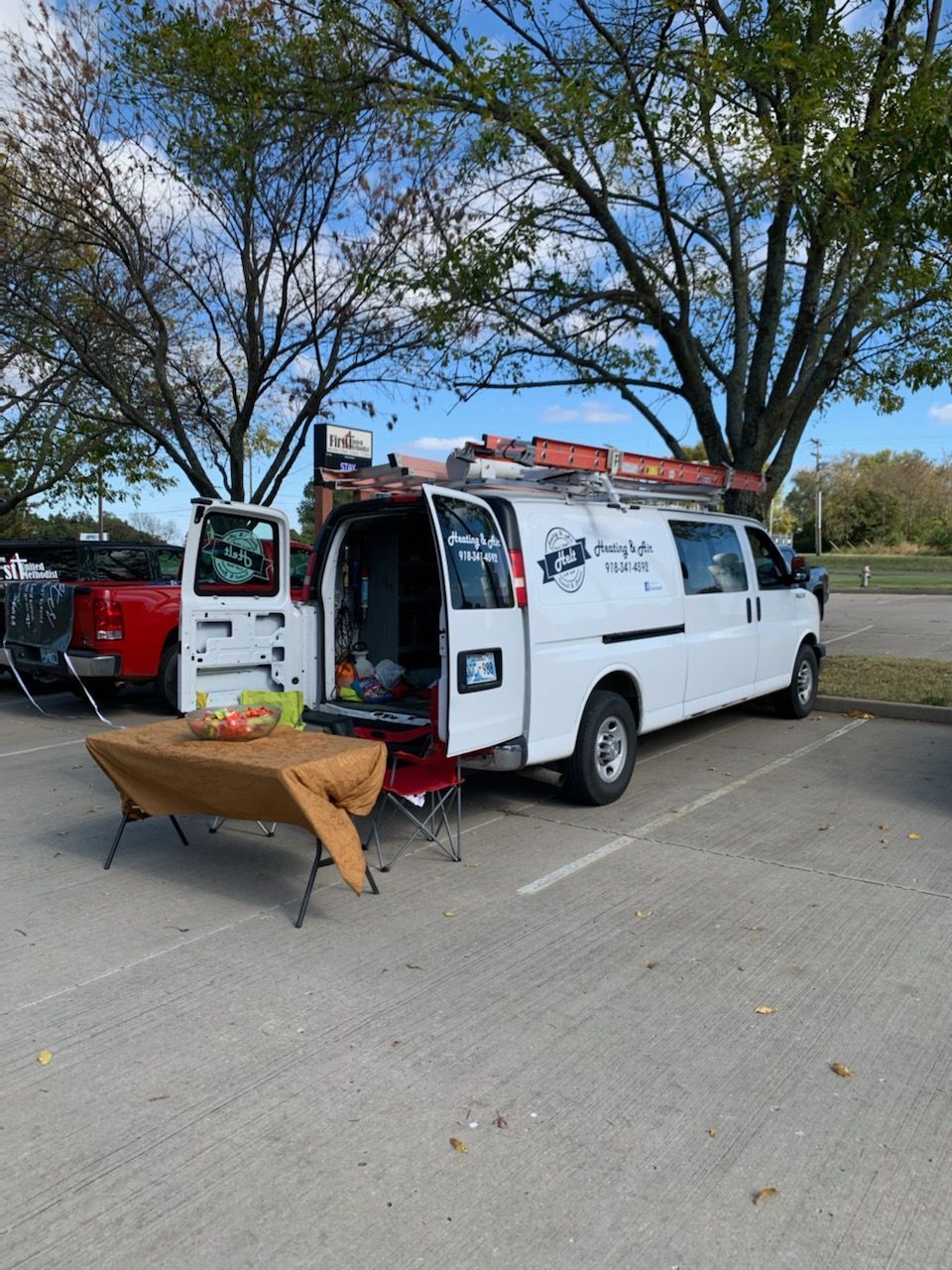 A white van is parked in a parking lot with its doors open.