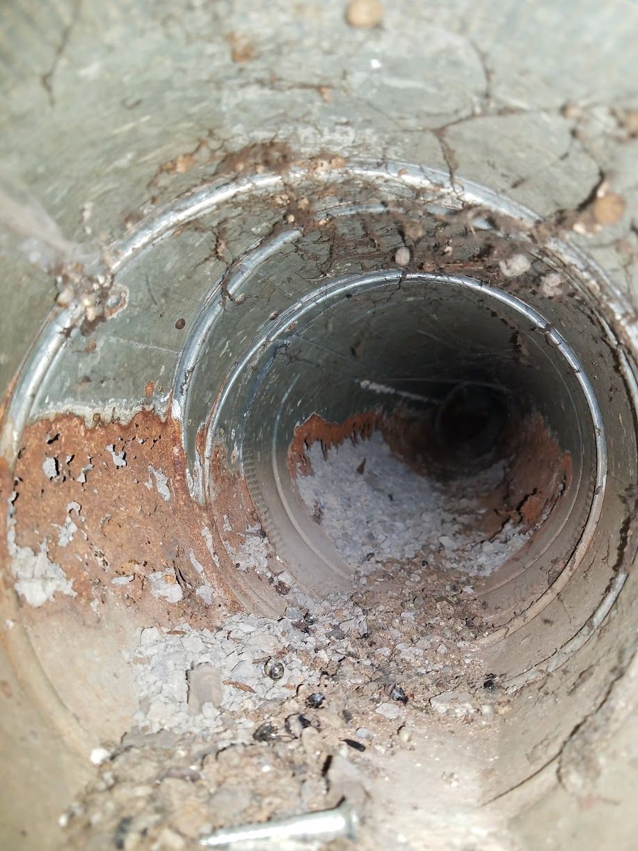 A close up of a dirty metal pipe with a hole in the middle.