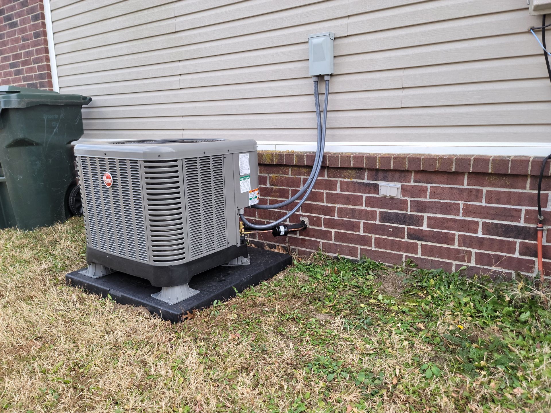 An air conditioner is sitting on the side of a brick building.