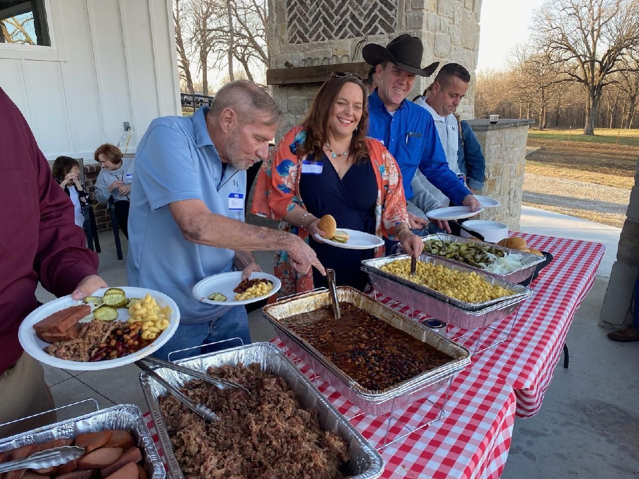 A group of people are standing around a table eating food.