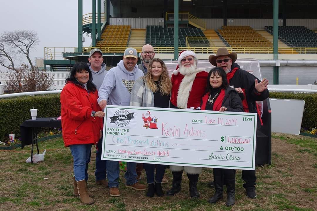 A group of people are posing for a picture with santa claus holding a large check.