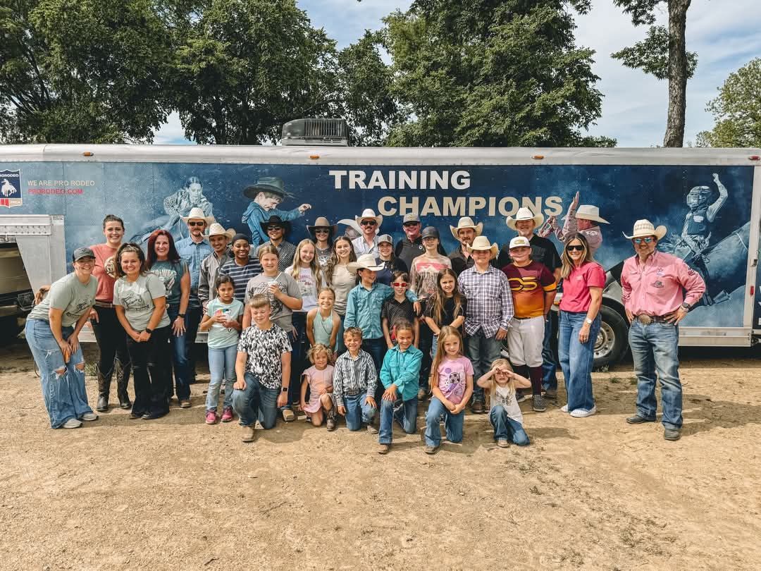 A group of people are posing for a picture in front of a training trailer.