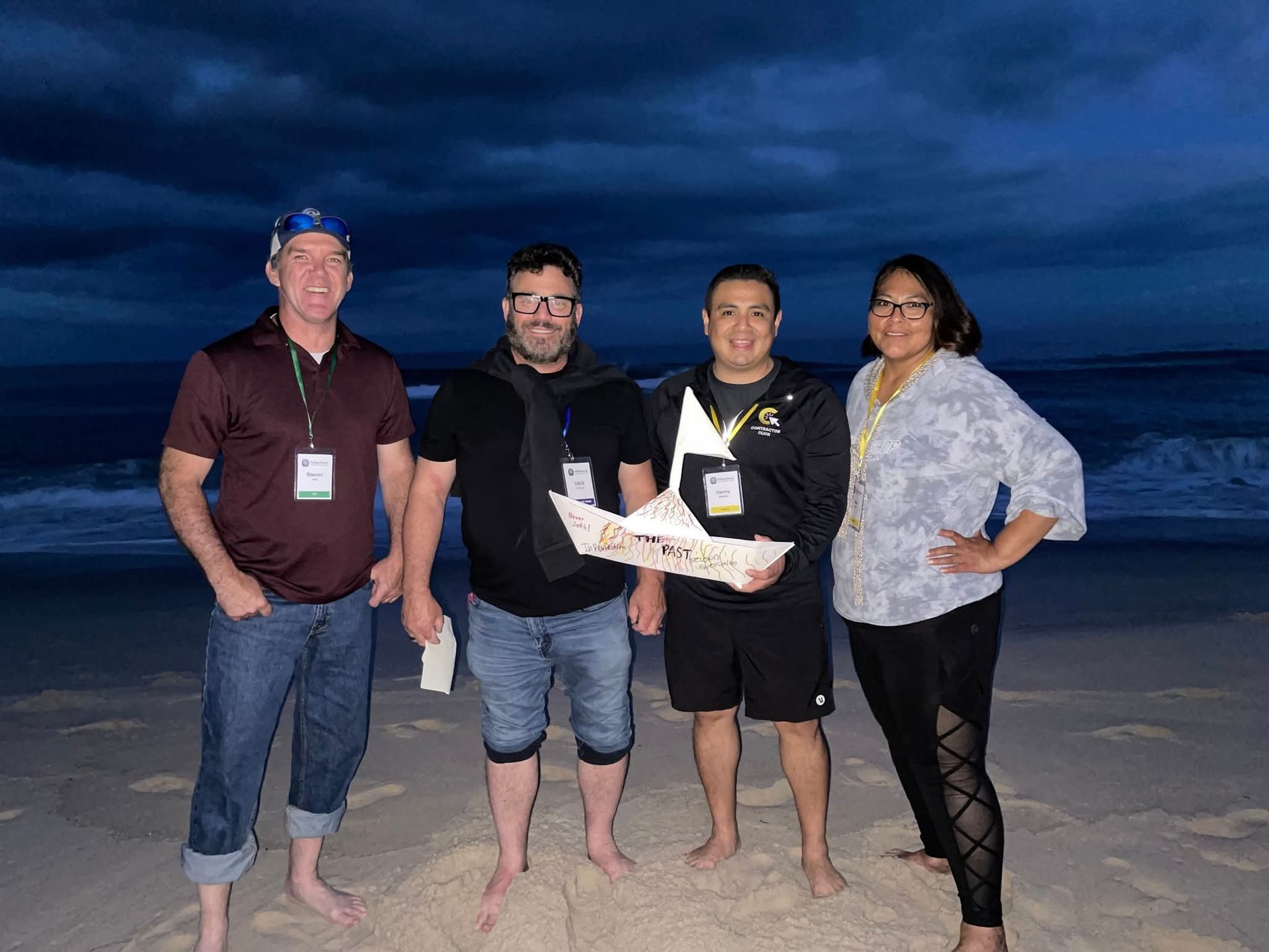 A group of people are standing on a beach holding a boat.