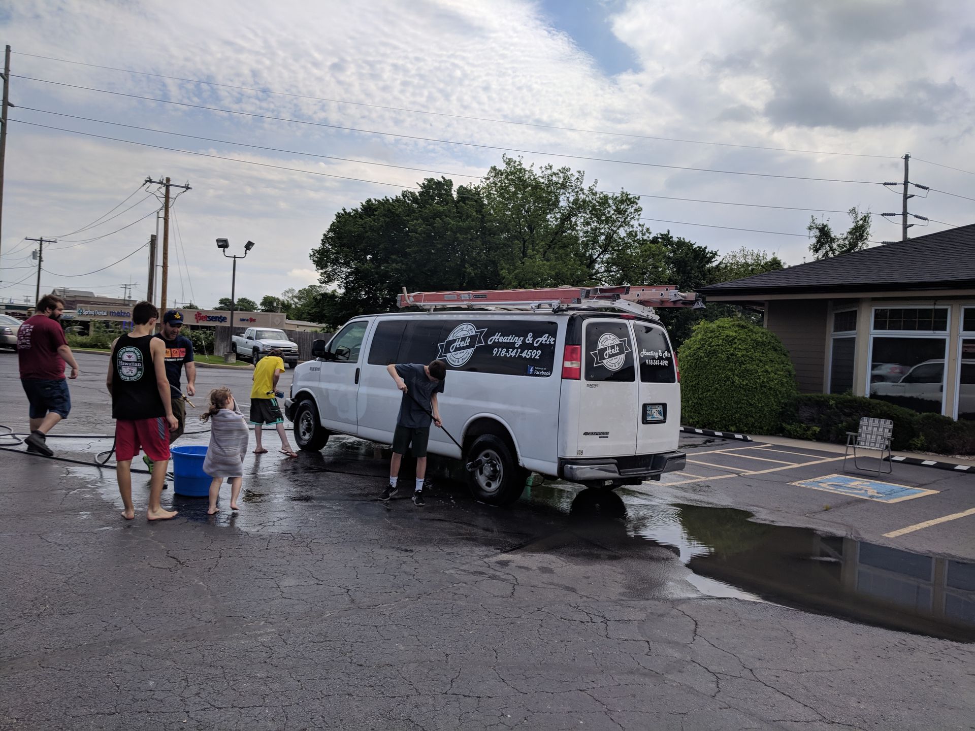 A group of people are washing a white van in a parking lot