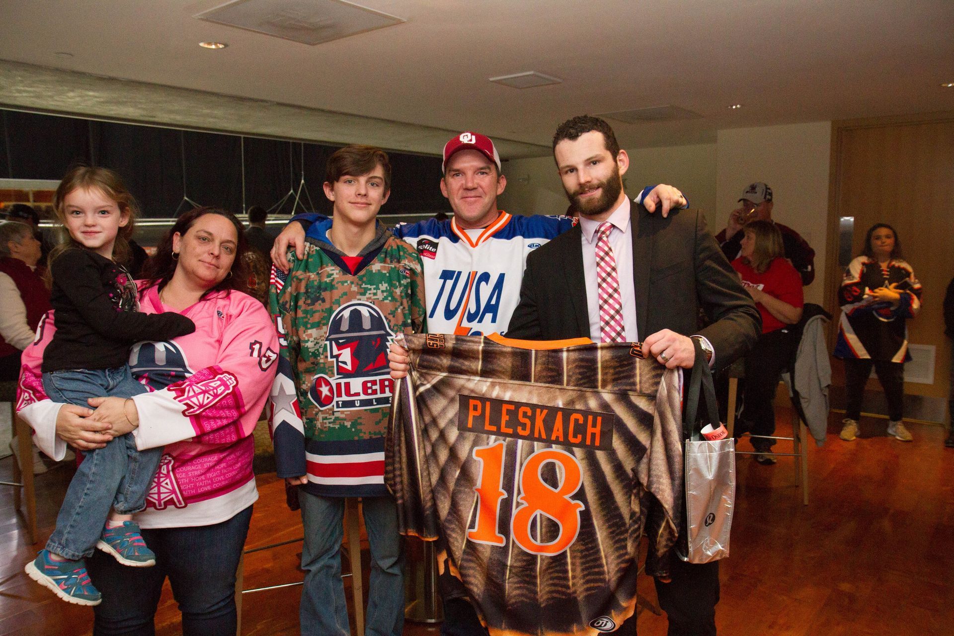 A group of people are posing for a picture and one of them is holding a jersey with the number 18 on it