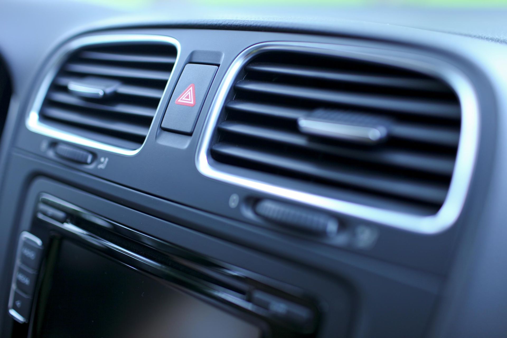 Dashboard with air vents and emergency flasher button in a car.
