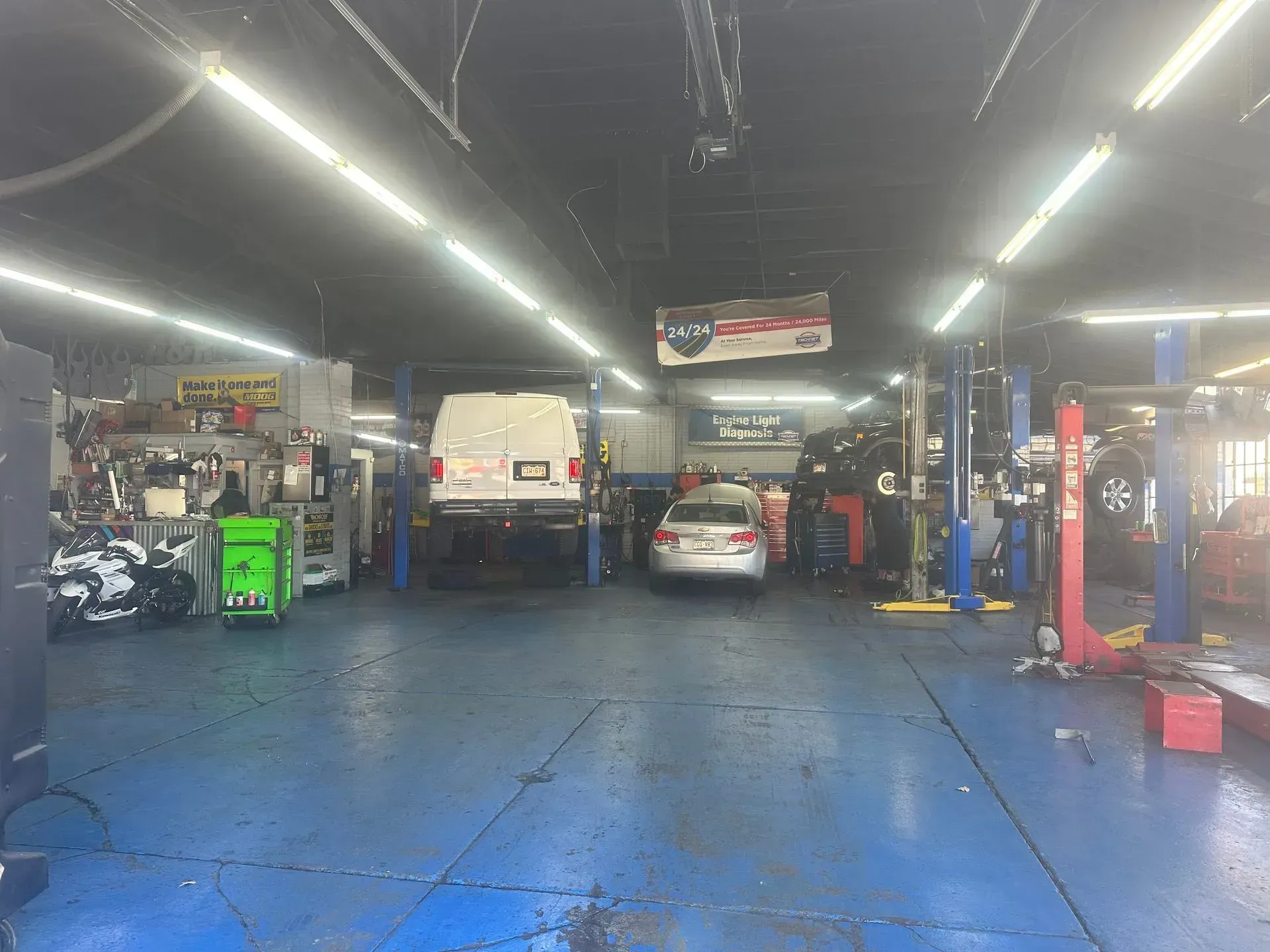 Interior of a car repair shop; several cars on lifts, tools, and equipment.