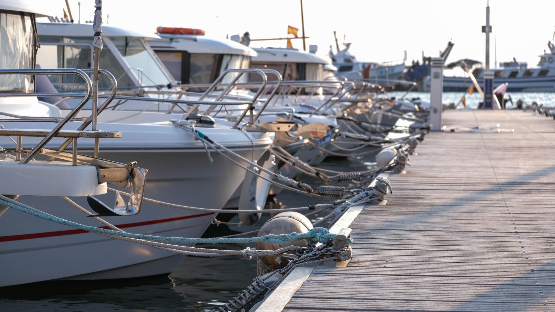 A row of boats are docked at a marina.