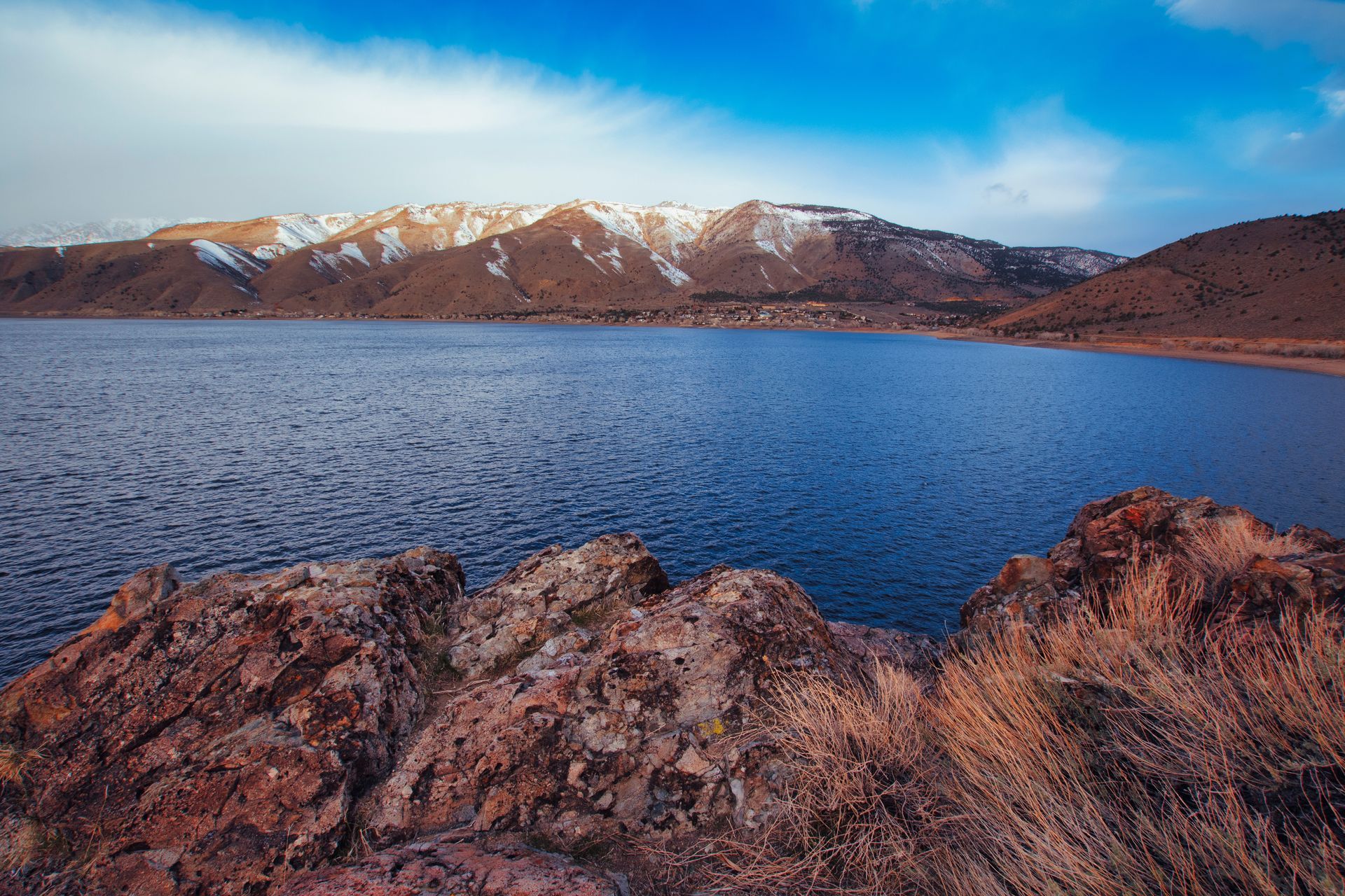 A lake with mountains in the background and rocks in the foreground.