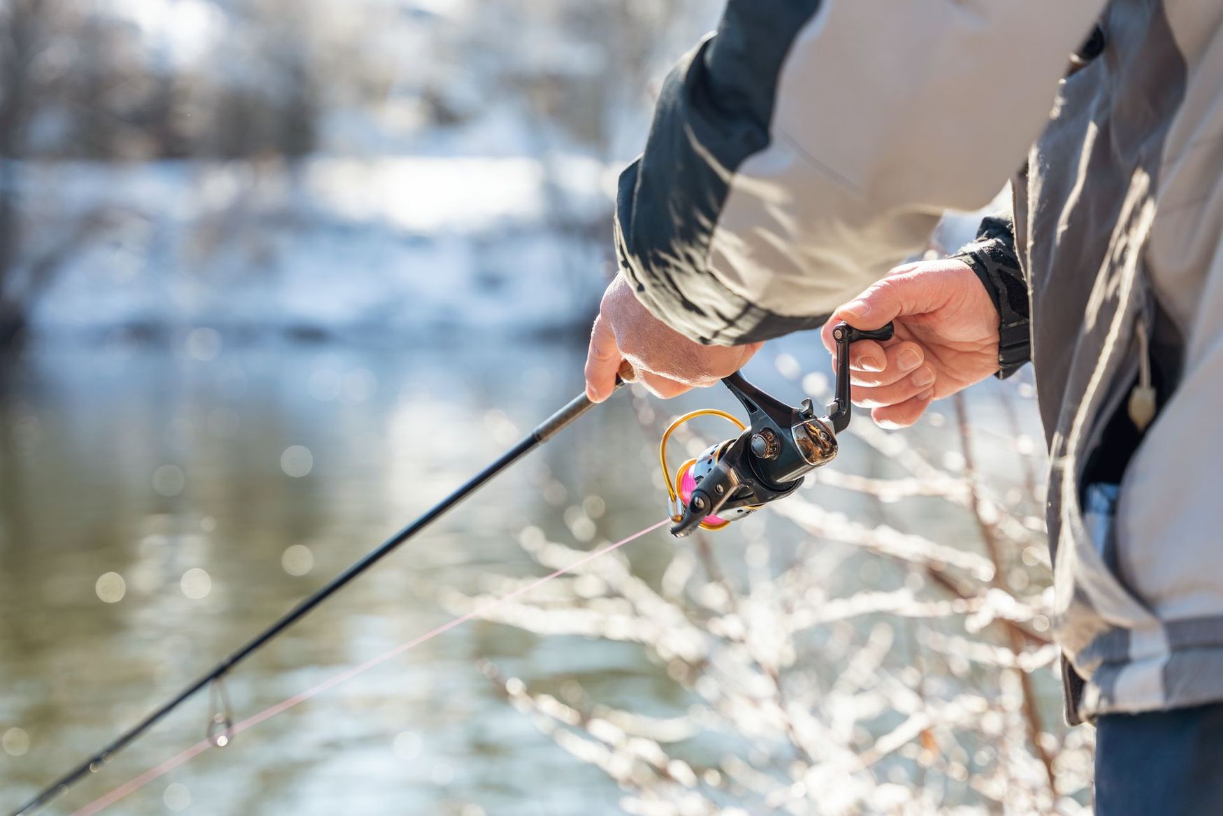 A man is holding a fishing rod in front of a river.