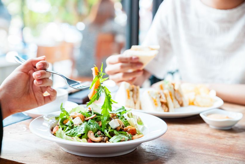 A person is eating a salad with a fork in a restaurant.