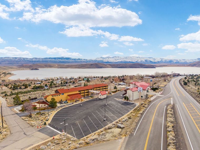 An aerial view of a road leading to a lake with mountains in the background.
