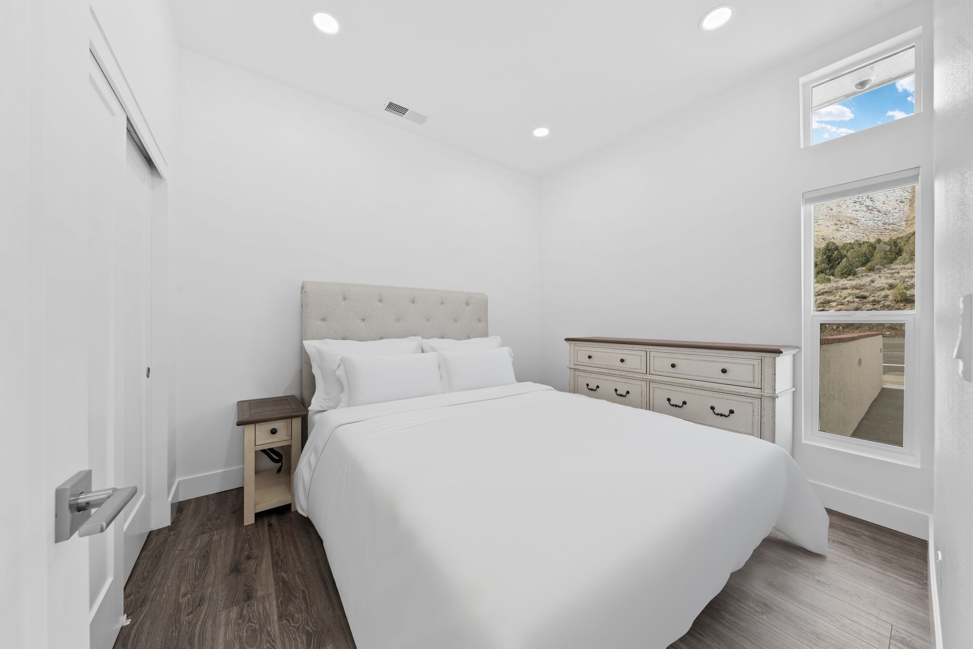 A bedroom with a bed , dresser , nightstand and window.