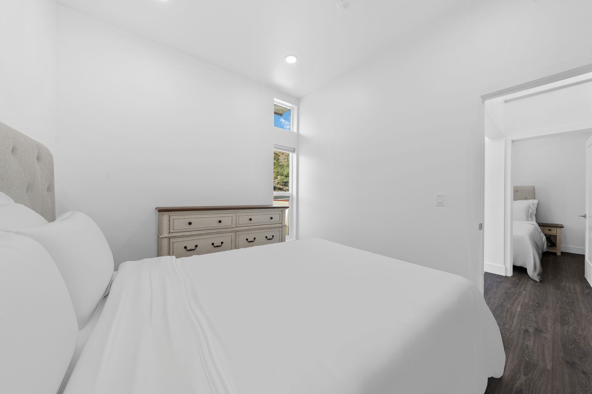 A bedroom with a bed , dresser , and window.