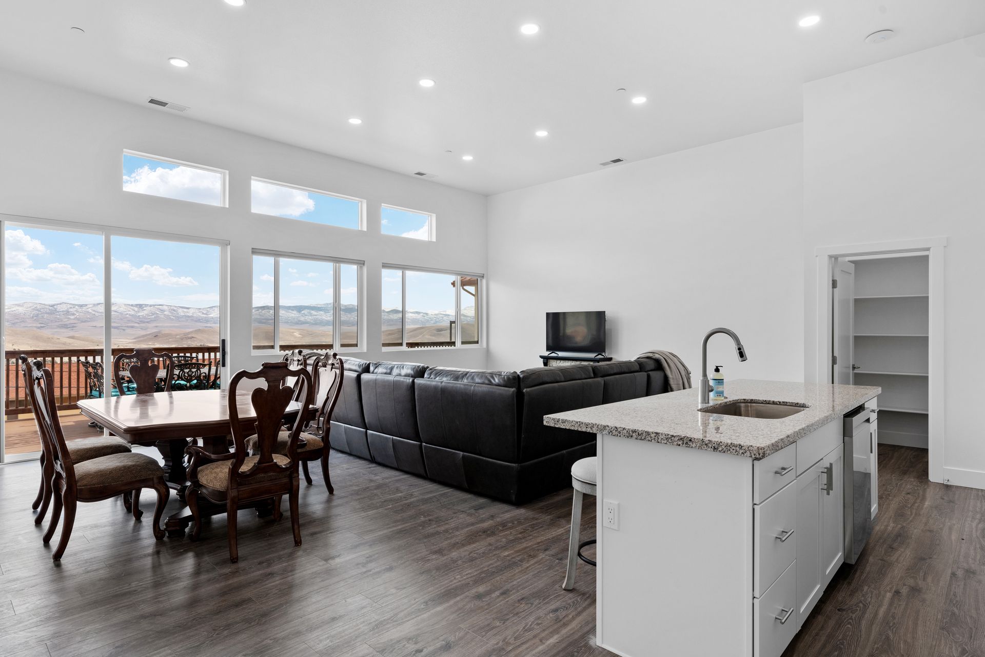 A living room with a couch , table , chairs and a kitchen.