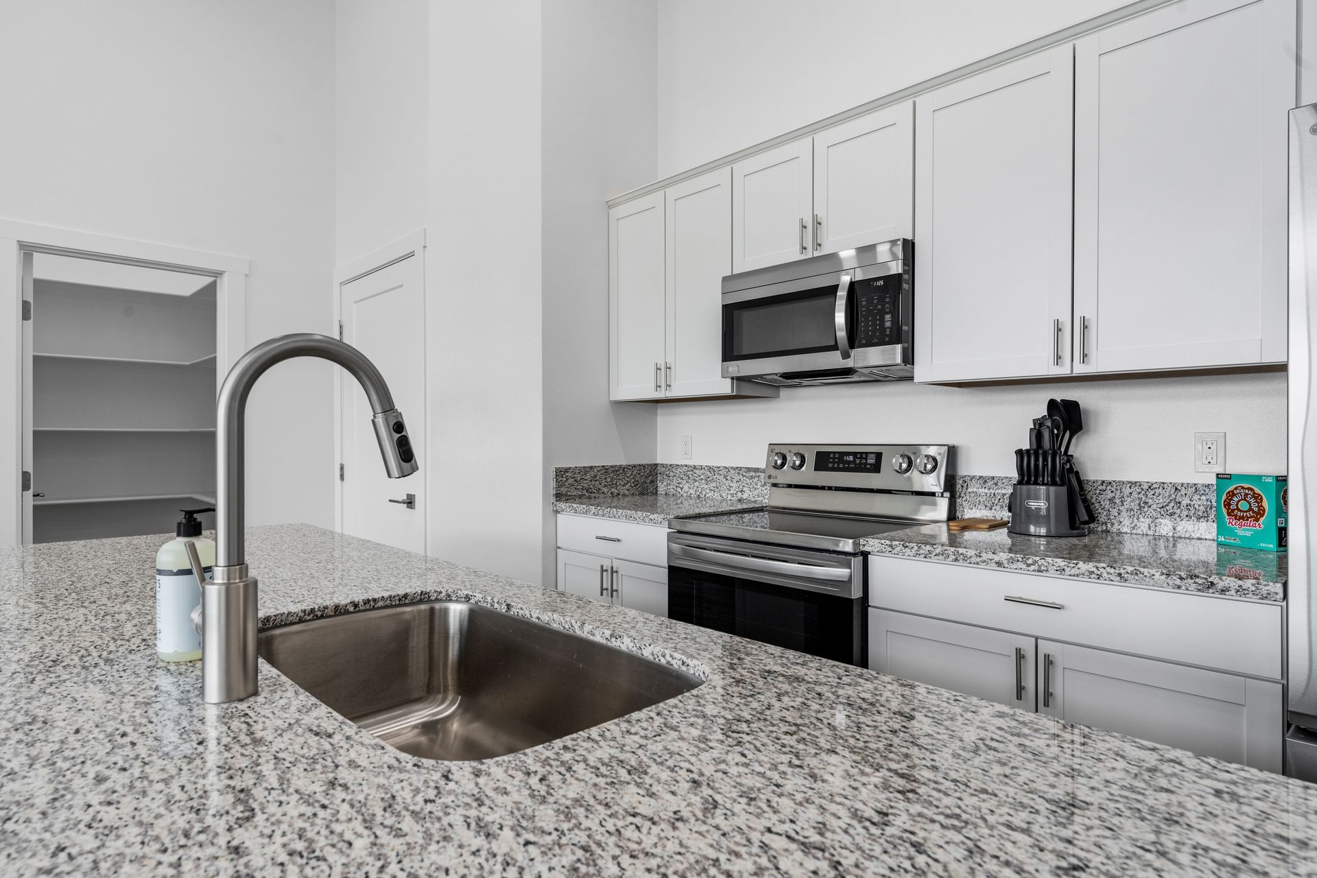 A kitchen with granite counter tops , stainless steel appliances , and white cabinets.