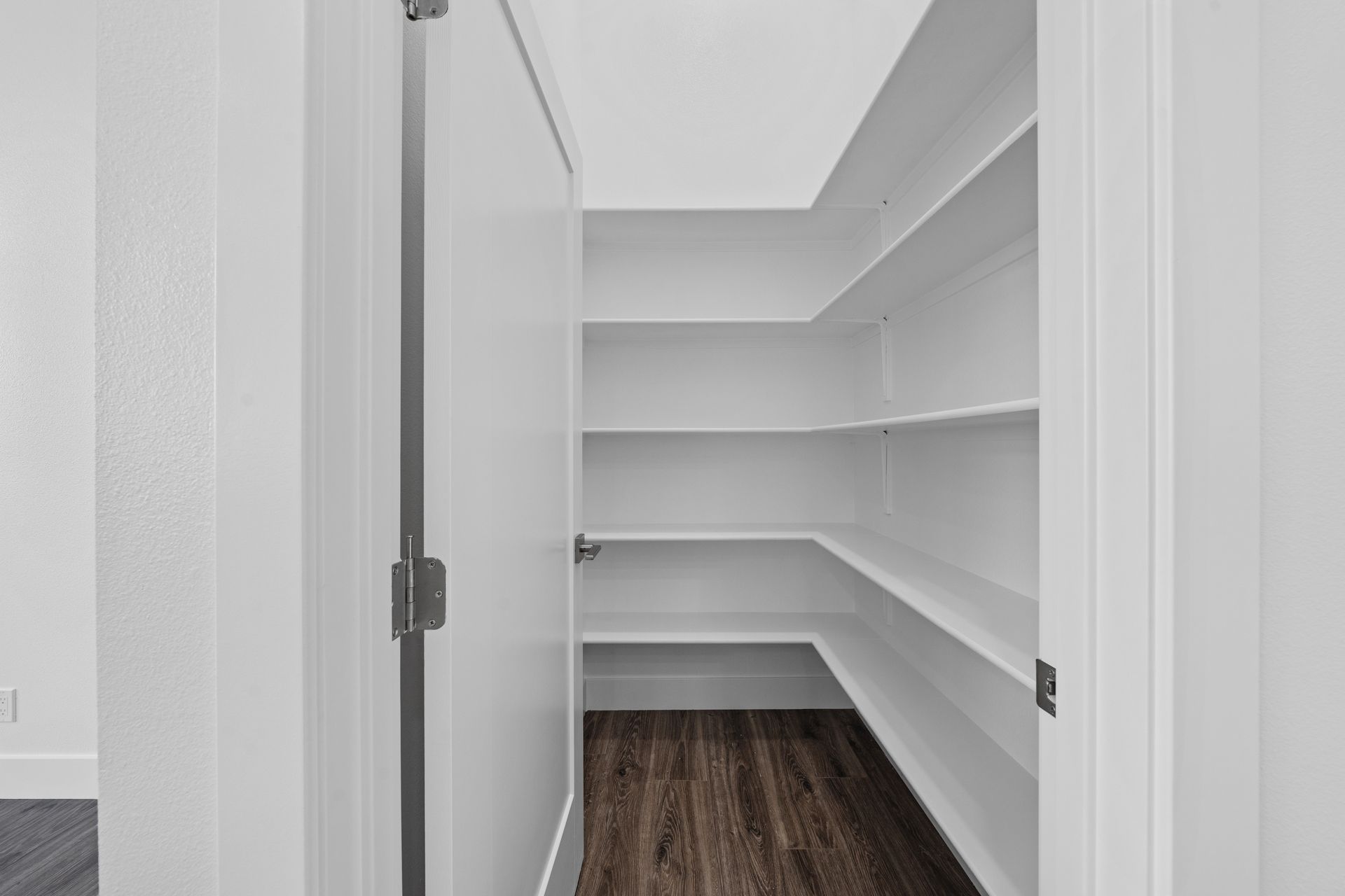 An empty pantry with shelves and a door in a house.