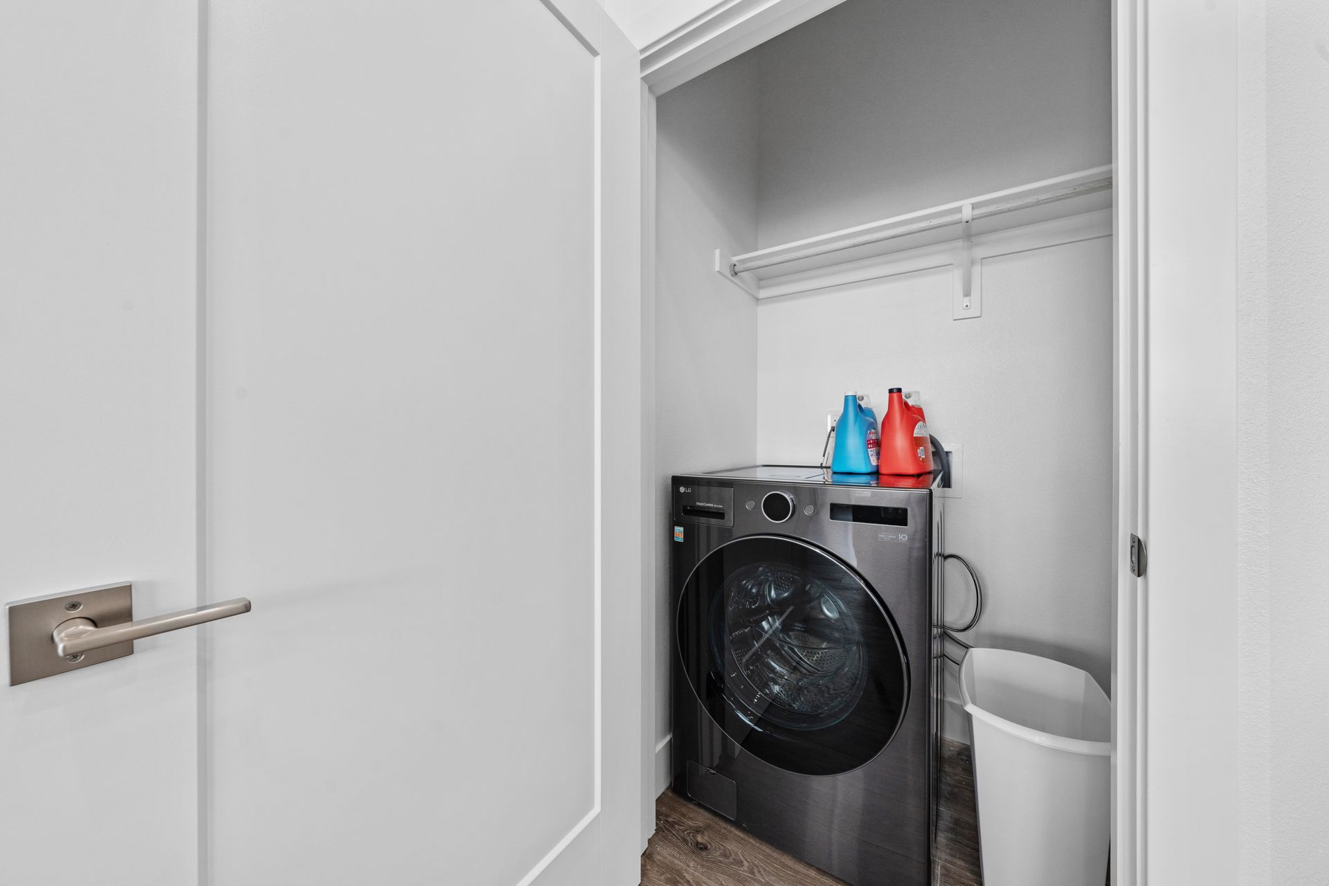 A laundry room with a washer and dryer and a trash can.