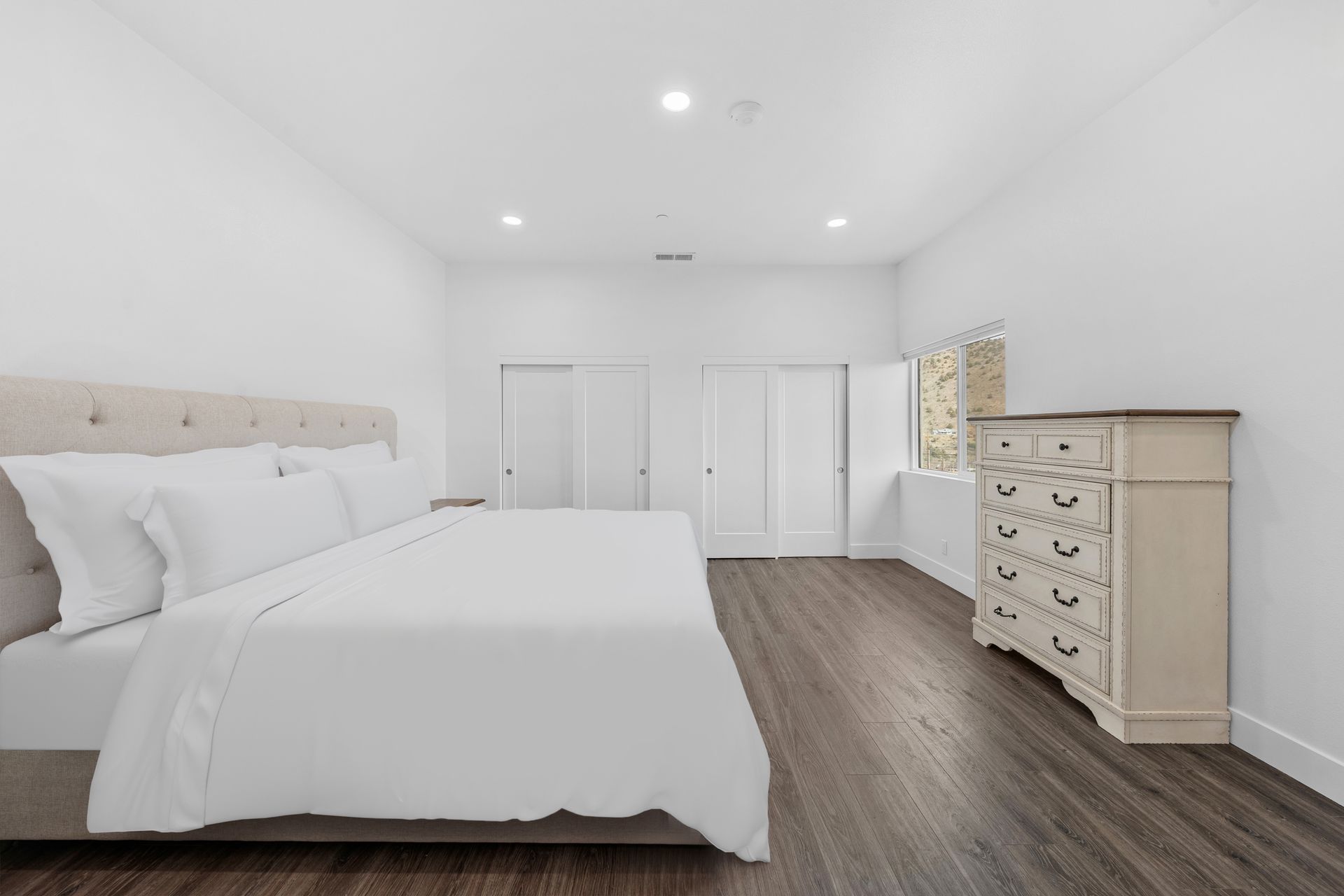 A bedroom with a king size bed , dresser , and mirror.