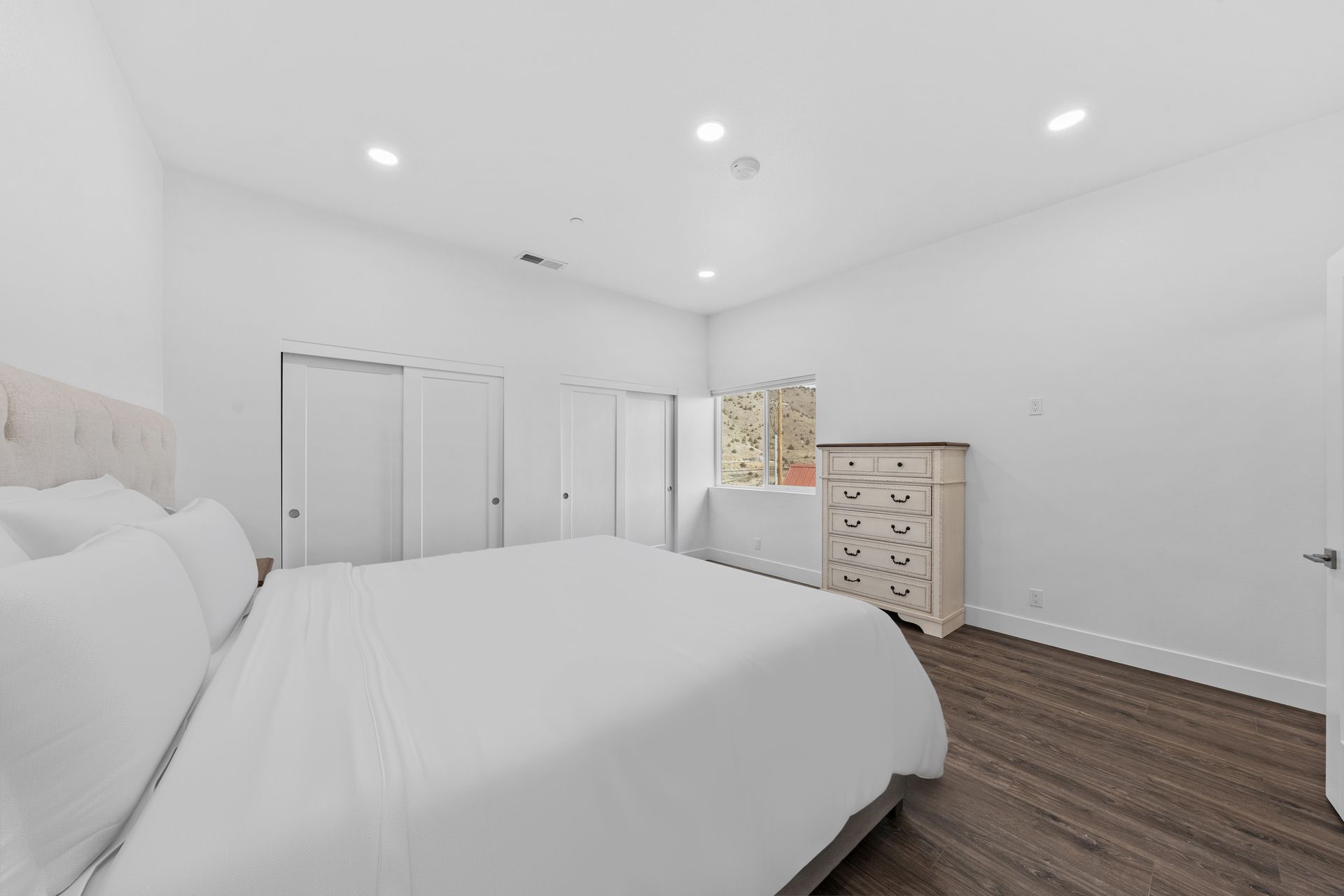 A bedroom with a large bed , dresser , and window.