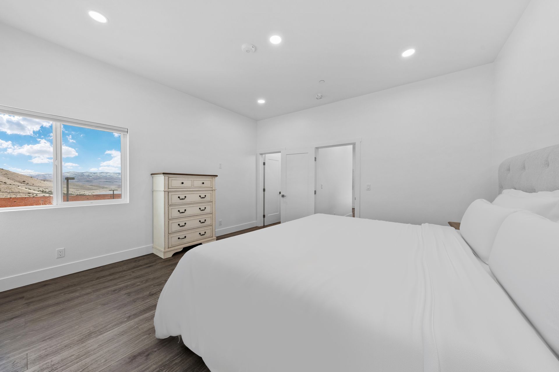 A bedroom with a bed , dresser , and window.