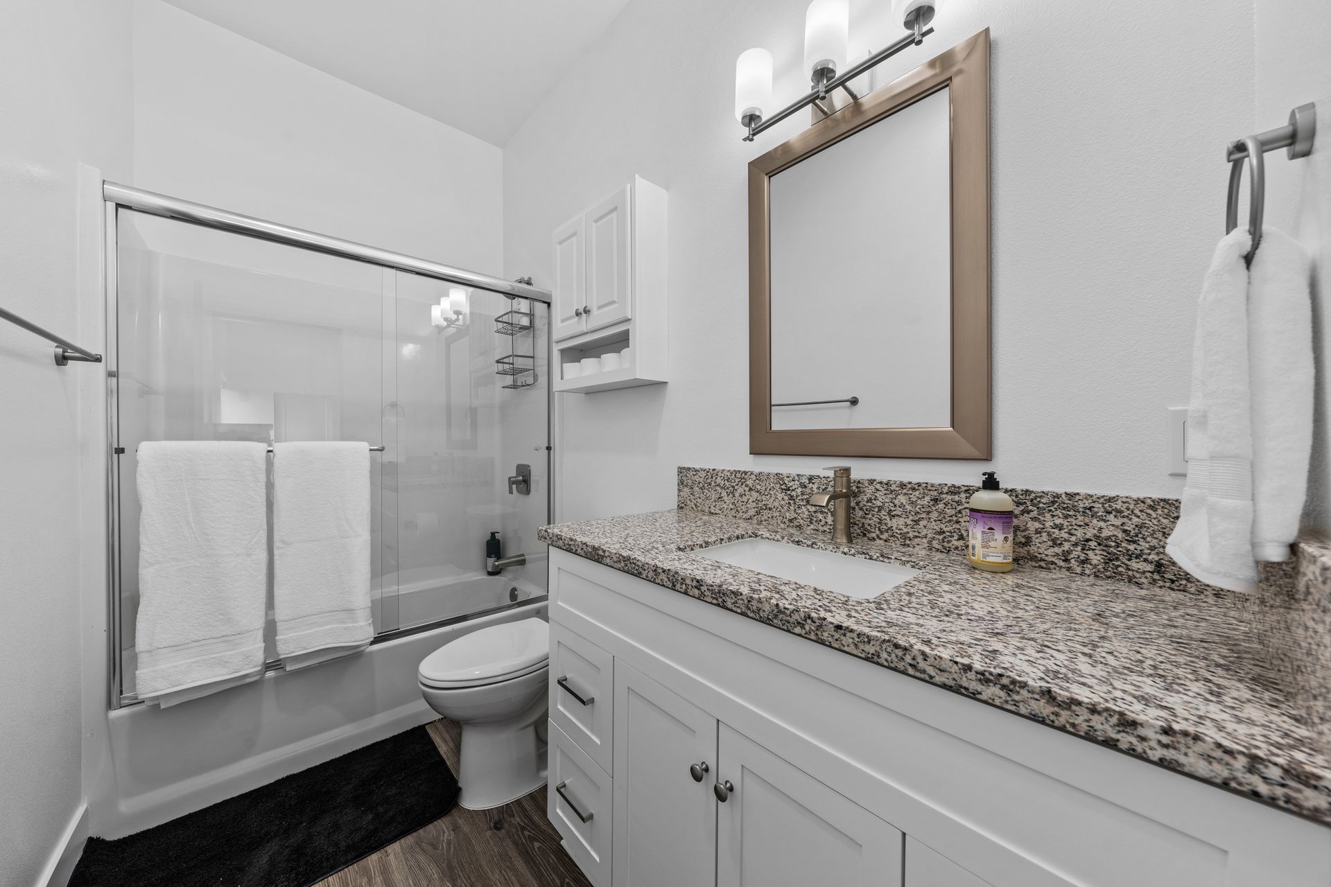 A bathroom with a toilet , sink , mirror and shower.