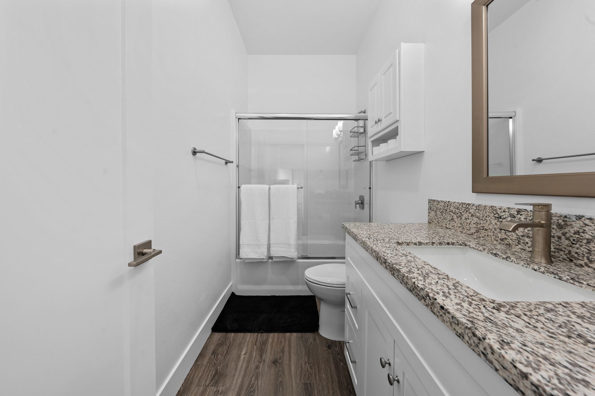 A bathroom with a sink , toilet , shower and mirror.