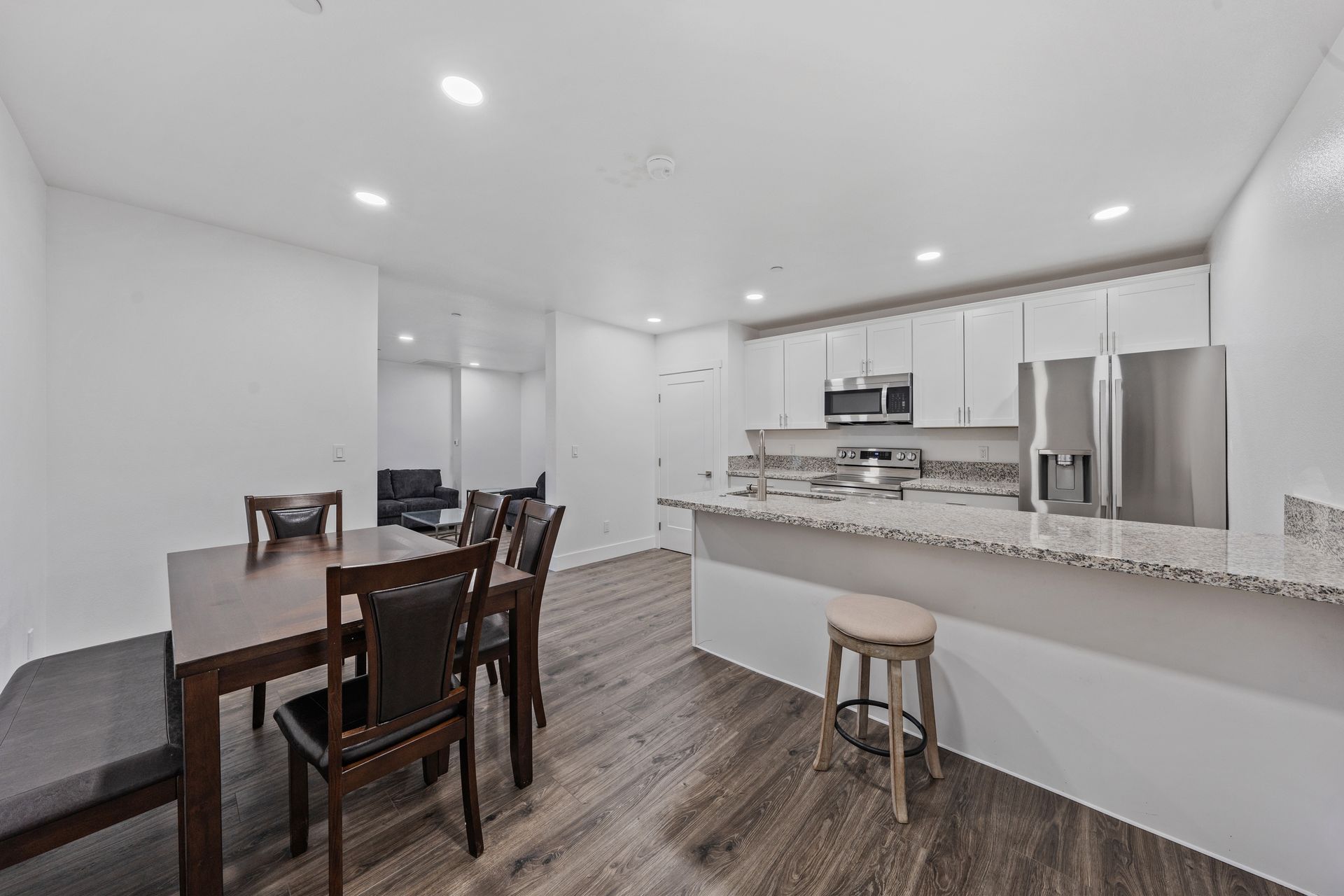 A kitchen with a table and chairs and a stainless steel refrigerator.